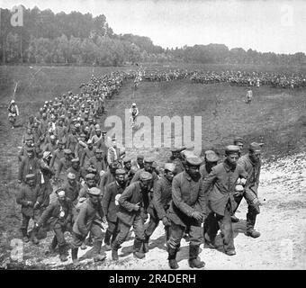 „Les „Douceurs“ de la Captivite; convoi de prisonniers en marche vers la gare d'Embarquement; le visage de beaucoup de ces hommes trahit la satisfaction d'enavoir fini avec les hasards de la bataille“, 1916. Aus „L'Album de la Guerre 1914-1919, Volume I“ [L'Illustration, Paris, 1924]. Stockfoto