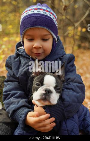 Ein Kind umarmt seinen geliebten Hund im Park. Stockfoto