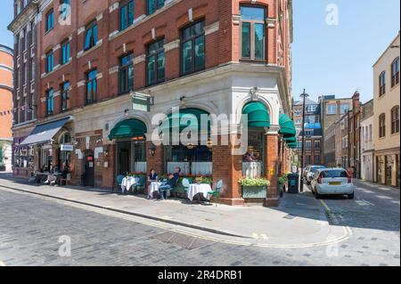 An einem sonnigen frühen Sommertag sitzen die Gäste an den Tischen vor dem Ivy Cafe und den St John Restaurants in der Marylebone Lane. London, England, Großbritannien Stockfoto