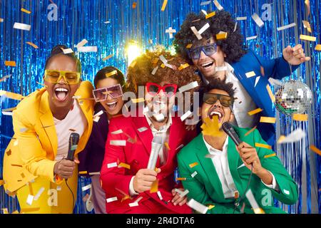 Eine Gruppe lustiger und lustiger Freunde singen auf einer Karaoke-Disco-Party im Nachtklub. Stockfoto