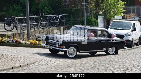 Bad Bentheim, Deutschland - 5 2023. Mai Ein Paar wird in einem schwarzen alten russischen Auto zu seiner Hochzeitszeremonie gefahren. Das Auto ist eine GAZ Volga 2. Generation Stockfoto