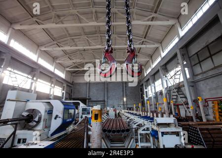 Zwei Kranhaken an der Kette, Nahaufnahme, im Fokus. Abstrakter Werkstattinnenraum verschwommen. Stockfoto