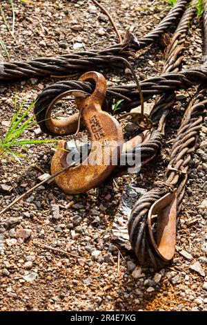 Nahaufnahme von verrostetem Stahlseil und Kranhaken auf Schotterhintergrund Stockfoto