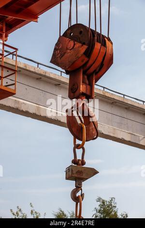 Nahaufnahme eines verrosteten Kranhakens am Stahlseil am blauen Himmel Stockfoto