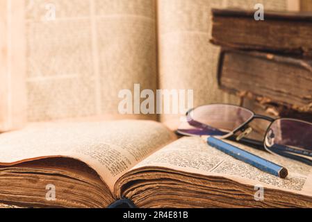 Alte, schäbige jüdische Bücher mit Lederbindung und offene, verschwommene Torah im Hintergrund. Torah-Studie. Nahaufnahme. Selektiver Fokus Stockfoto