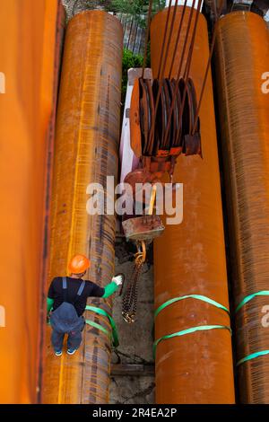 Arbeiter, verrostete Rohre und Kranhaken Stockfoto