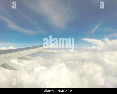 Luftbild aus einem kommerziellen Flugzeug im Flug, im Hintergrund können Sie den Flügel des Flugzeugs sehen, im Hintergrund den hellblauen Himmel Stockfoto