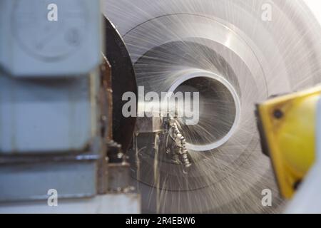 Bearbeitungsrohr auf Drehmaschine. Nahaufnahme. Wasserkühlung des Werkzeugs. Stahlspäne (Späne). Stockfoto