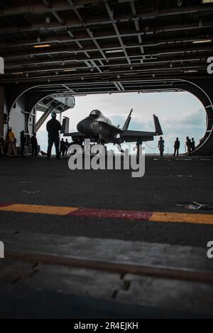 Matrosen, die an Bord des Flugzeugträgers USS George Washington der Nimitz-Klasse (CVN 73) der Flugabteilung zugeteilt sind, bringen ein F/A-18C Hornet, ein Trainingsflugzeug in die Hangarbucht an Bord der USS George Washington der Nimitz-Klasse (CVN 73) in Newport News, Virginia, 28. März 2023. George Washington wird im Newport News Shipbuilding den Tankkomplex überholen (RCOH). RCOH ist ein mehrjähriges Projekt, das nur einmal während der 50-jährigen Lebensdauer eines Frachtführers durchgeführt wird und das Betanken der beiden Kernreaktoren des Schiffs sowie umfangreiche Reparaturen, Aufrüstungen und Modernisierungen umfasst. (USA Navy Foto von Mass Comm Stockfoto