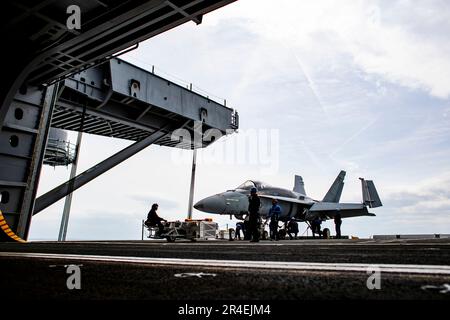 Matrosen, die an Bord des Flugzeugträgers USS George Washington (CVN 73) der Nimitz-Klasse der Flugabteilung zugeteilt sind, bereiten sich auf den Transport eines F/A-18C Hornet vor, das Trainingsflugzeug in die Hangarbucht an Bord der USS George Washington der Nimitz-Klasse (CVN 73) in Newport News, Virginia, 28. März 2023. George Washington wird im Newport News Shipbuilding den Tankkomplex überholen (RCOH). RCOH ist ein mehrjähriges Projekt, das nur einmal während der 50-jährigen Lebensdauer eines Frachtführers durchgeführt wird und das Betanken der beiden Kernreaktoren des Schiffs sowie umfangreiche Reparaturen, Aufrüstungen und Modernisierungen umfasst. (USA Navy Foto B Stockfoto