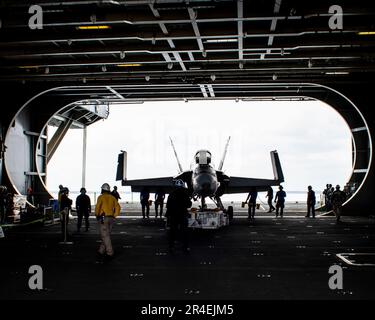 Matrosen, die an Bord des Flugzeugträgers USS George Washington der Nimitz-Klasse (CVN 73) der Flugabteilung zugeteilt sind, bringen ein F/A-18C Hornet, ein Trainingsflugzeug in die Hangarbucht an Bord der USS George Washington der Nimitz-Klasse (CVN 73) in Newport News, Virginia, 28. März 2023. George Washington wird im Newport News Shipbuilding den Tankkomplex überholen (RCOH). RCOH ist ein mehrjähriges Projekt, das nur einmal während der 50-jährigen Lebensdauer eines Frachtführers durchgeführt wird und das Betanken der beiden Kernreaktoren des Schiffs sowie umfangreiche Reparaturen, Aufrüstungen und Modernisierungen umfasst. (USA Navy Foto von Mass Comm Stockfoto