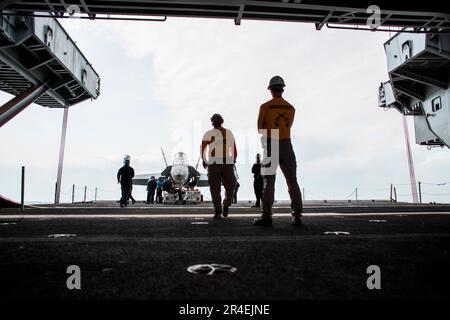 Matrosen, die an Bord des Flugzeugträgers USS George Washington (CVN 73) der Nimitz-Klasse der Flugabteilung zugeteilt sind, bereiten sich auf den Transport eines F/A-18C Hornet vor, das Trainingsflugzeug in die Hangarbucht an Bord der USS George Washington der Nimitz-Klasse (CVN 73) in Newport News, Virginia, 28. März 2023. George Washington wird im Newport News Shipbuilding den Tankkomplex überholen (RCOH). RCOH ist ein mehrjähriges Projekt, das nur einmal während der 50-jährigen Lebensdauer eines Frachtführers durchgeführt wird und das Betanken der beiden Kernreaktoren des Schiffs sowie umfangreiche Reparaturen, Aufrüstungen und Modernisierungen umfasst. (USA Navy Foto B Stockfoto