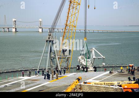 Matrosen, die der Luftabteilung an Bord des Flugzeugträgers USS George Washington (CVN 73) der Nimitz-Klasse zugeteilt sind, laden in Newport News, Virginia, am 20. April 2023 einen Absturzkran eines Trägerschiffs auf das Schiff. George Washington wird im Newport News Shipbuilding den Tankkomplex überholen (RCOH). RCOH ist ein mehrjähriges Projekt, das nur einmal während der 50-jährigen Lebensdauer eines Frachtführers durchgeführt wird und das Betanken der beiden Kernreaktoren des Schiffs sowie umfangreiche Reparaturen, Aufrüstungen und Modernisierungen umfasst. (USA Marinefoto von Mass Communication Specialist 3. Class Nicholas A. Russell) Stockfoto