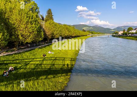 Das Ufer der Salzach mit Blick auf die Festung Hohensalzburg und die Kathedrale quatier ist ein beliebter Ort für ein Picknick für Paare in Salzburg, Österreich Stockfoto