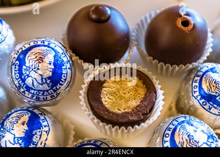 Die Herstellung einer Mozartkugel mit einem Marzipankern und einer Nugat- und Schokoladenhülle ist aufwendige Handwerkskunst in der Konditorei Fürst in Salzburg, Österreich. 1905 gewann die Praline eine Goldmedaille auf der Internationalen Produktausstellung in Paris. Ihr Erfinder hat sie nie patentieren lassen, und seitdem hat es weltweit unzählige Nachahmer gegeben. Stockfoto
