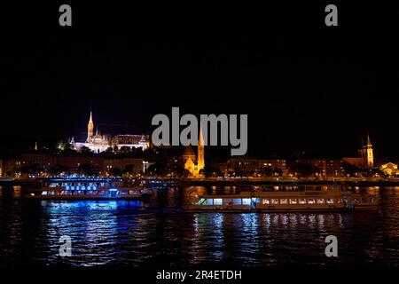 Budapest Nachtlandschaft mit vielen Laternen und beleuchteten Gebäuden. Ein Vergnügungsboot segelt auf dem Fluss. Budapest, Ungarn - 08.24.2022 Stockfoto
