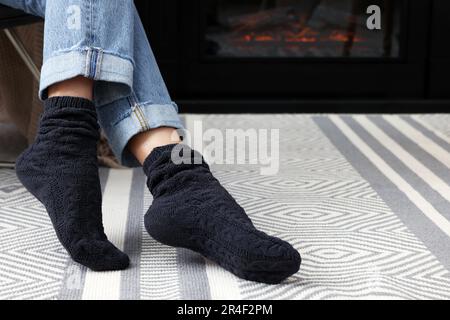 Eine Frau in warmen Socken, die sich zu Hause am Kamin entspannt Stockfoto