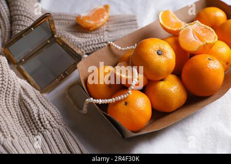 Pappschachtel mit frischen, reifen Tangerinen und Einrichtung auf weißem Stoff, Blick von oben Stockfoto