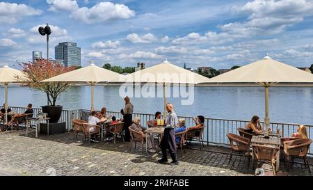 An einem wunderschönen Sommertag entspannen sich die Menschen auf der Terrasse der Schokoladenfabrik am Rhein in Deutschland. Stockfoto