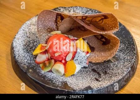 Crepe mit Eiscreme, Schlagsahne und Erdbeersauce. Stockfoto