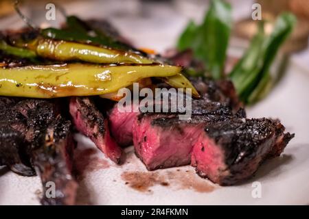 Carne asada, ein gegrilltes und in Scheiben geschnittenes Ribeye-Rindfleisch, serviert auf einem Teller mit Zwiebeln Toreado. Es ist ein mexikanisches Gericht. Stockfoto