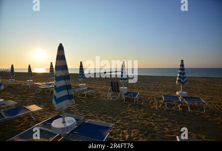 Die Sonne geht am frühen Morgen auf dem noch einsamen Strand auf Stockfoto