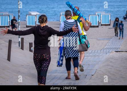 Rostock, Deutschland. 28. Mai 2023. Die ersten Urlauber gehen morgens mit ihrer Strandausrüstung an den Strand an der Ostseeküste. Mit viel Sonnenschein und hohen Temperaturen zeigt das Wetter seine beste Seite am Pfingstsonntag in Norddeutschland. Kredit: Jens Büttner/dpa/Alamy Live News Stockfoto