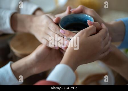 Familie hält eine Tasse Tee in den Händen, wärmt sich in einer kalten Wohnung Stockfoto
