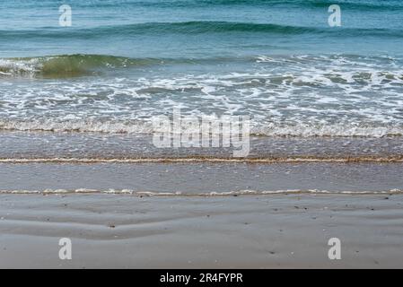 Sanfte Wellen brechen an einem Sandstrand. Stockfoto