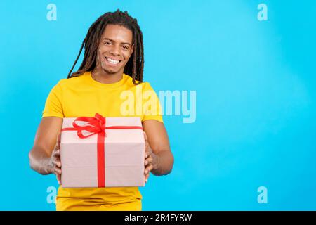 Ein glücklicher latino mit Dreadlocks, der ein Geschenk macht Stockfoto