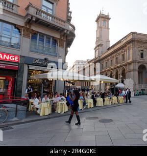 Lady in Black spaziert vorbei an der Bar Duomo gegenüber dem Palazzo dei Giureconsulti in der Stadt Mailand, Lombardei, Italien Stockfoto