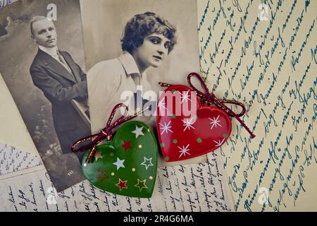 Alte Fotos von Mann und Frau auf alten, handgeschriebenen Briefen und zwei Herzen Stockfoto