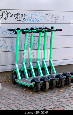 Sechs elektrische Roller parken in einem Park in der Nähe einer Mauer Stockfoto