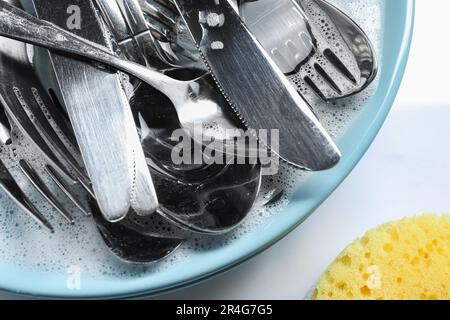 Platte mit Besteck in Schaumstoff und Schwamm auf weißem Hintergrund, flach verlegt Stockfoto