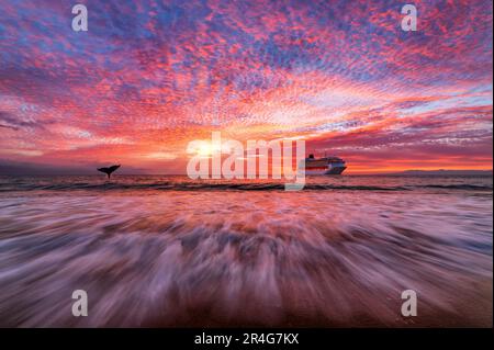 Ein Kreuzschiff, das auf dem Ozean unter einem farbenfrohen Sonnenuntergangshimmel sitzt Stockfoto