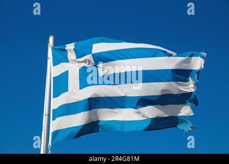 Eine leicht zerrissene griechische Nationalflagge, die im Wind winkt Stockfoto