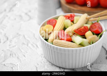 Schmackhafter Babymais mit Gemüse und Champignons auf einem grau strukturierten Tisch, Nahaufnahme. Platz für Text Stockfoto