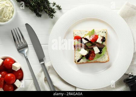 Flach liegend mit köstlichem Sardellen-Sandwich auf weißem Holztisch Stockfoto