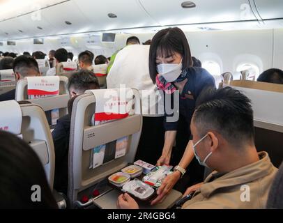 Shanghai, Chinas erster selbst entwickelter Rumpf-Jetliner. 28. Mai 2023. Ein Flugbegleiter serviert einem Passagier eine Flugmahlzeit an Bord eines C919 großen Passagierflugzeugs, Chinas erstem selbst entwickelten Kofferjet, von Shanghai nach Peking am 28. Mai 2023. Der C919, Chinas selbst entwickeltes großes Passagierflugzeug, schloss seinen ersten kommerziellen Flug von Shanghai nach Peking am Sonntag ab und markierte damit seinen offiziellen Eintritt in den zivilen Luftverkehr. Kredit: Ding Ting/Xinhua/Alamy Live News Stockfoto