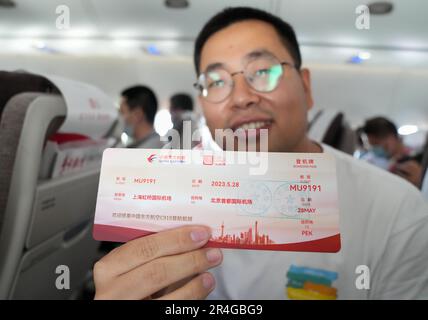Shanghai, Chinas erster selbst entwickelter Rumpf-Jetliner. 28. Mai 2023. Ein Passagier zeigt eine Bordkarte an Bord eines C919 großen Passagierflugzeugs, Chinas erstem selbst entwickelten Kofferraumflugzeug, von Shanghai nach Peking am 28. Mai 2023. Der C919, Chinas selbst entwickeltes großes Passagierflugzeug, schloss seinen ersten kommerziellen Flug von Shanghai nach Peking am Sonntag ab und markierte damit seinen offiziellen Eintritt in den zivilen Luftverkehr. Kredit: Ding Ting/Xinhua/Alamy Live News Stockfoto