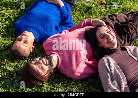 Freunde, die sich an einem sonnigen Tag auf dem Rasen ausruhen Stockfoto