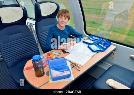 Ein Junge im Zug, macht Hausaufgaben, Deutschland, Regionalzug Stockfoto