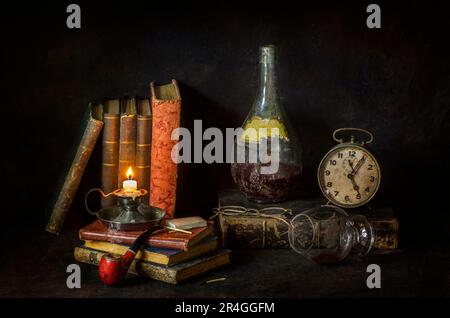 Klassisches Stille Leben mit alten Büchern mit alter Weinflasche, Uhr, Glas Wein, Pfeife und klassisch beleuchteter Kerze auf rustikalem dunklem Hintergrund Stockfoto