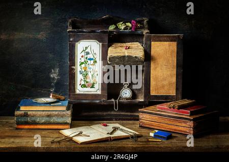 Klassisches Stille Leben mit alten Büchern mit altem Schrank mit trockener Blume, Taschenuhr, Zigarre, Gläsern und alter Schachtel auf altem Hintergrund. Stockfoto