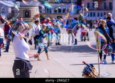 Rostock, Deutschland. 28. Mai 2023. Ein Blasenkünstler unterhält Urlauber und Tagesgäste auf der Strandpromenade in Warnemünde. Mit viel Sonnenschein und warmen Temperaturen zeigt sich das Wetter am Whitsunday in Norddeutschland von seiner besten Seite. Kredit: Jens Büttner/dpa/Alamy Live News Stockfoto