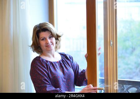 Frau öffnet oder schließt Fenster zum Balkon Stockfoto