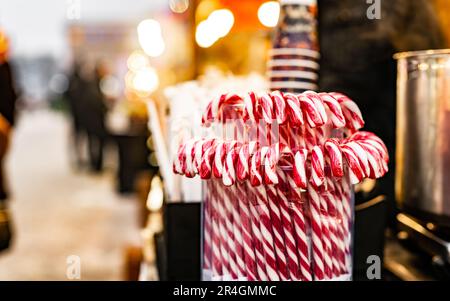 Traditionelle weihnachtliche Lollipop-Zuckerstangen mit rot-weißen Streifen auf dem traditionellen Street Food Festival-Markt. Festliche Süßigkeiten auf der Messe als Symbol von Weihnachten Stockfoto