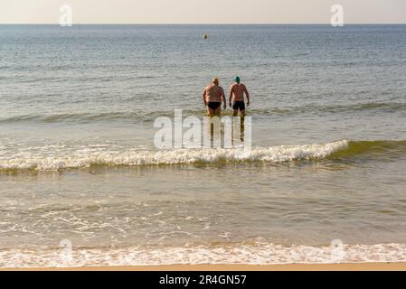 Bournemouth, Dorset, Großbritannien, Sonntag, 28. Mai 2023, Wetter. Zwei Männer gehen am Branksome Chine Beach ans Meer, an dem heißesten Tag des Jahres und an einem Frühjahrswochenende. Kredit: Paul Biggins/Alamy Live News Stockfoto