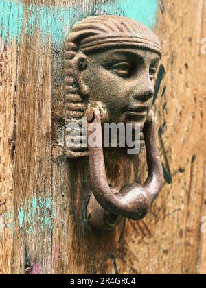 Türklopfen, Selektivfokus, menschliches Gesicht oder kopfförmiger Klopfen der alten Holztür. Stockfoto