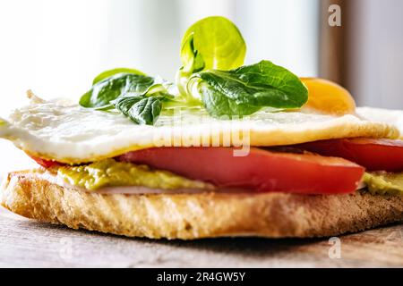 Getoastetes Brot mit Ei, Tomaten und Spinat für ein gesundes Proteinfrühstück. Leckeres Morgensandwich für schnelle Diät Stockfoto